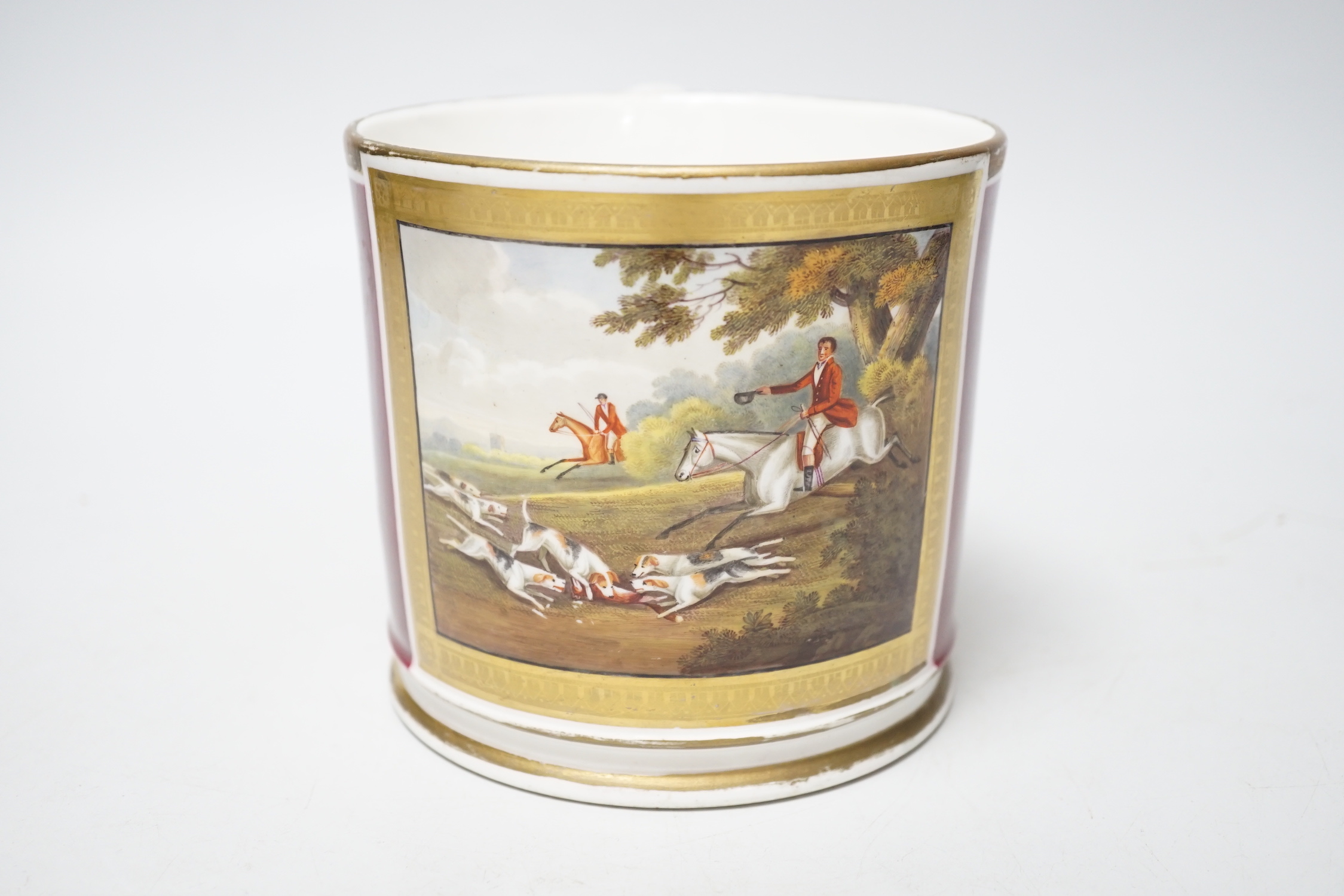 A 19th century English porcelain mug painted horses and riders with hunting dogs in a chase scene, the mug having a crimson ground, probably Chamberlains or Grainger’s Worcester, some old re-gilding